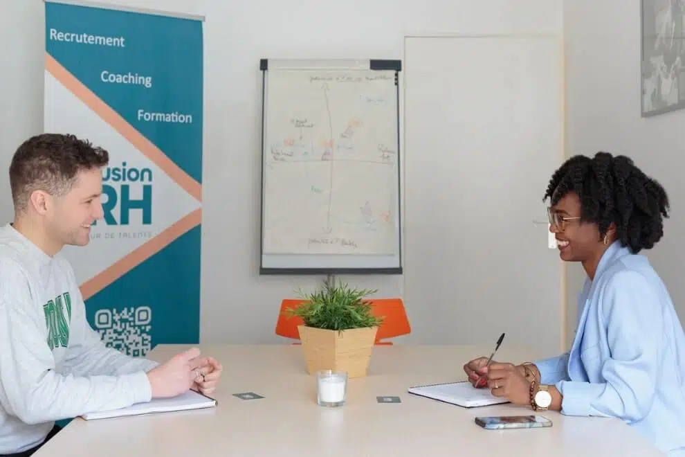 Un homme et une femme sont assis face à face, discutant dans une salle de réunion.